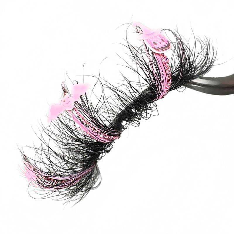 3D Mink Halloween Lash Extensions. Pink Glitter Infused Color Lashes. Pink Lashes With Pink And Black Spider, Bat, And Pumpkin Lash Decals. 25mm Eyelashes With Fluffy Wispy Volume. Eyelashes For Halloween Costumes.